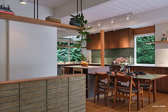 West Coast modern post-and-beam in West Vancouver with glass walls, lush garden, and deck over carport.