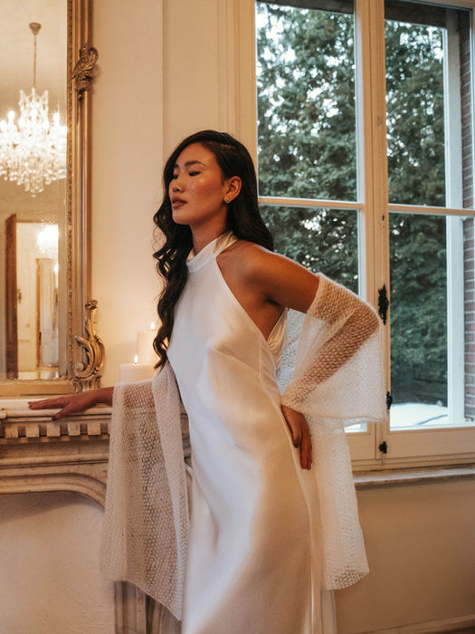 Strakke witte cocktailjurk met lange mouwen en kanten details.