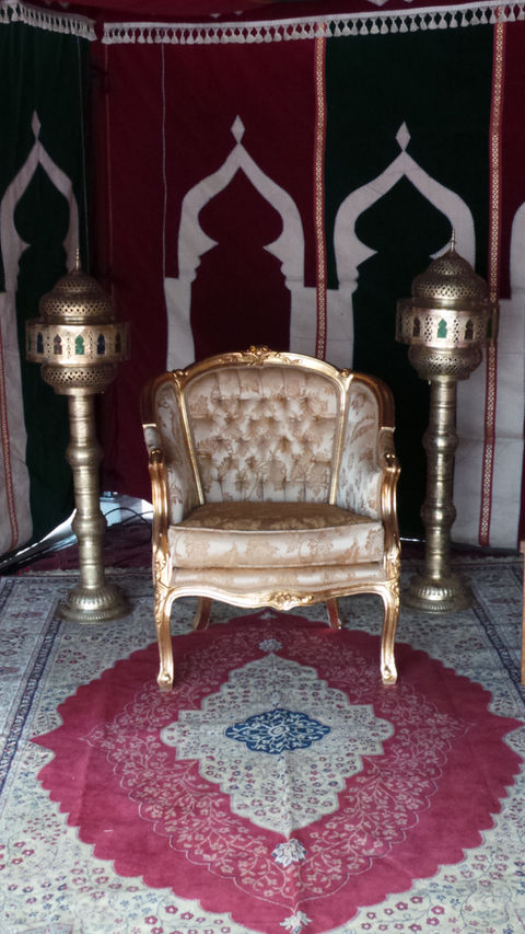 a gold chair sits in front of two brass lamps