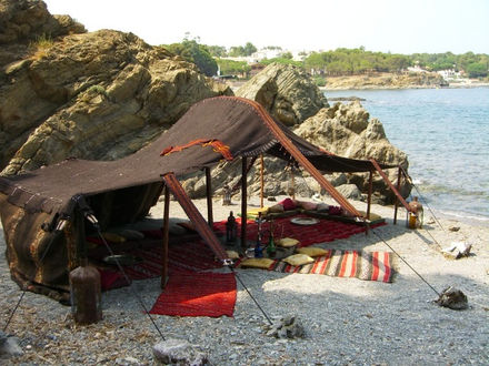 a large tent sits on a rocky beach near the water