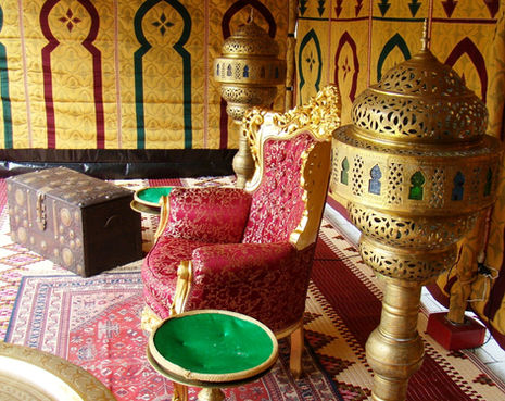 a chair with a red cushion sits in front of a gold lantern