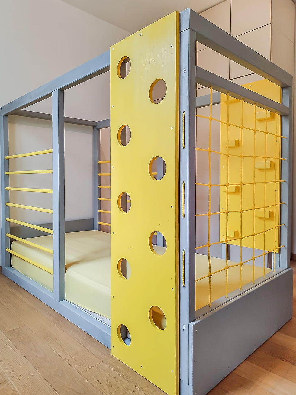 Eye-level view of a low wooden Montessori bed in a bright child's bedroom