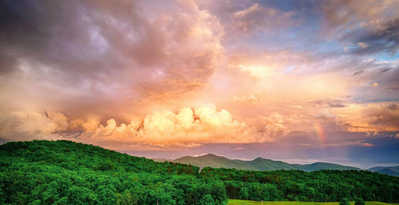 Vibrant sunset over a green landscape, trees and red barn, mountains visible, Kimberley Mierzwa Photography. Drone Photography Lexington, Va.