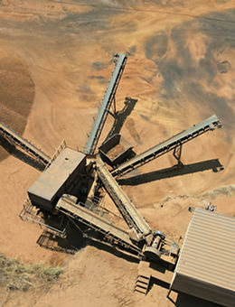 Imagem aérea de solo em processo de britagem, com máquina operando na fragmentação de materiais.