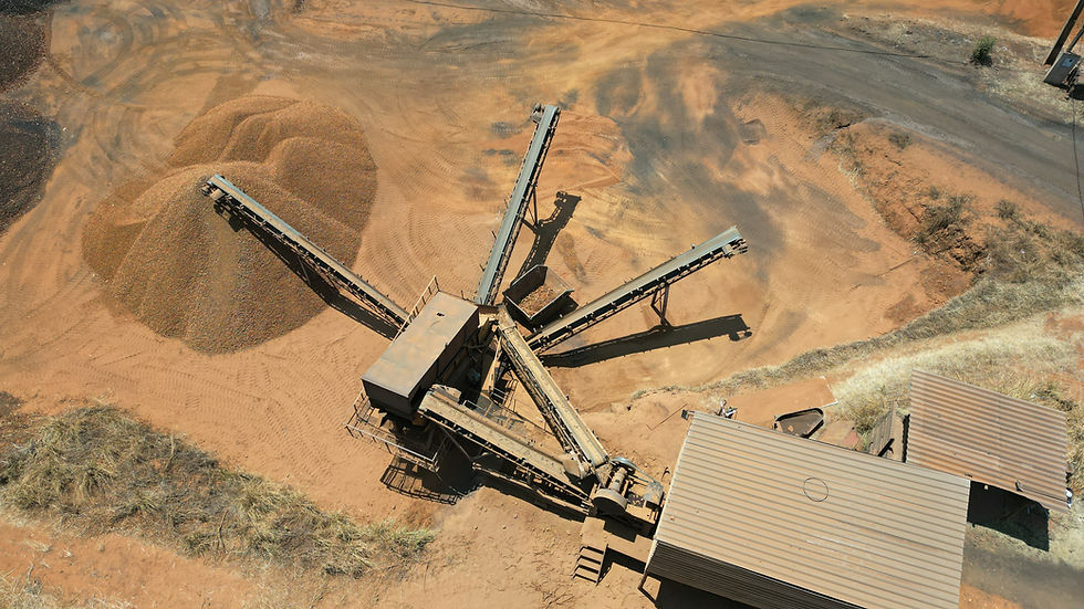 Imagem aérea de solo em processo de britagem, com máquina operando na fragmentação de materiais.