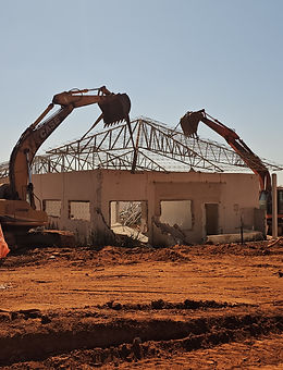 Máquina pesada realizando a demolição de uma estrutura na propriedade, removendo entulhos