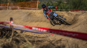 A Mountain Bike rider kicking up dust on a berm during Downhill racing in Portugal