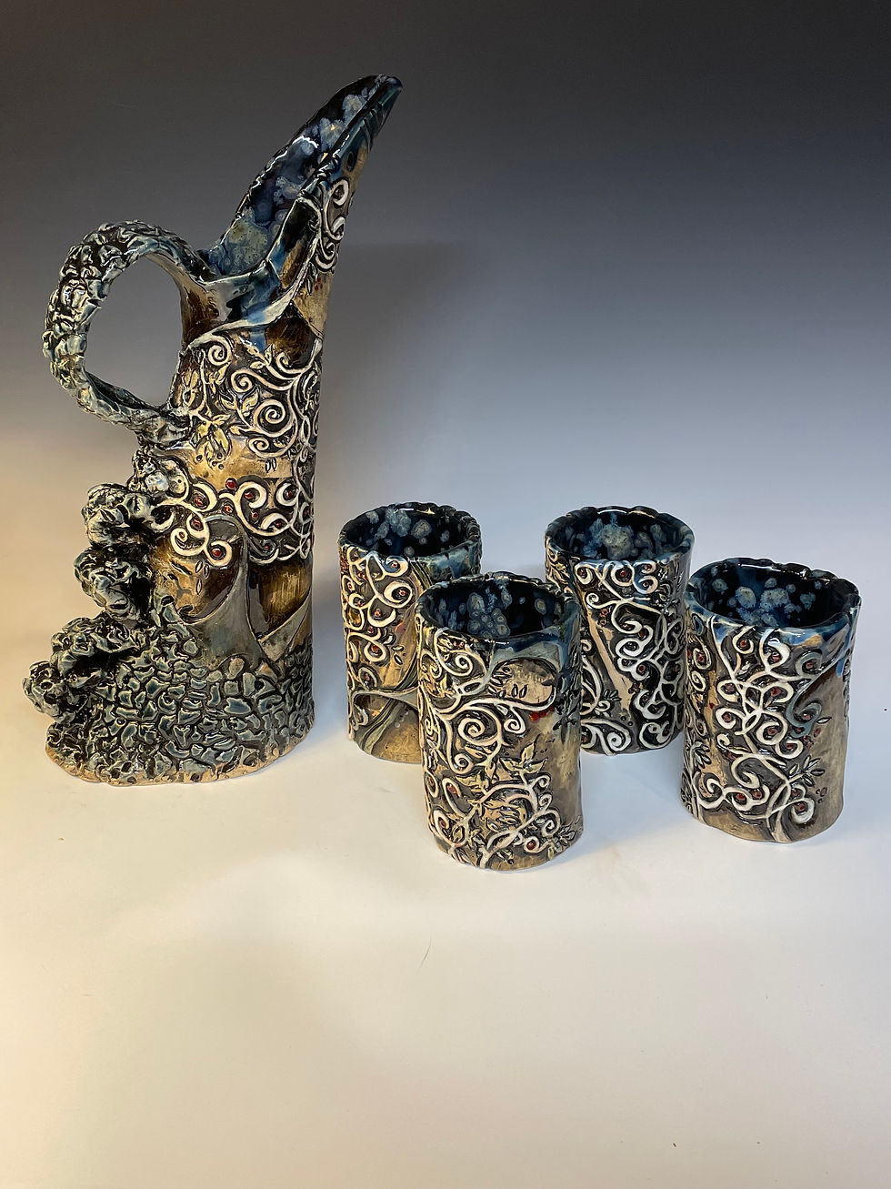 intricate pitcher with four cups