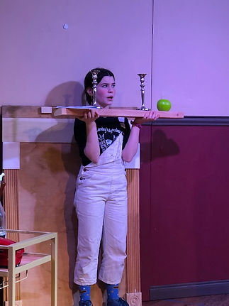 Teen girl acting on stage in a colorful costume in The Play That Goes Wrong One Act.