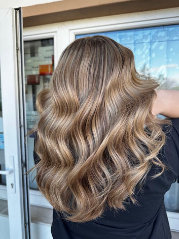 ALT-Text:
Warme Balayage mit weichen Beige- und Caramel Blondtönen sowie sanften Wellen im Salon von Sabine Jecho in Marchegg.