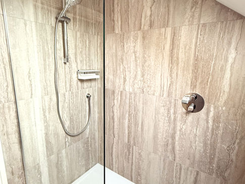 a shower with a glass door and a shower head