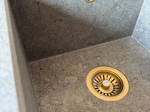 Stone sink with brass drain, minimalist design.