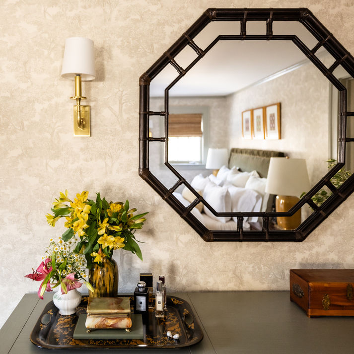 A primary bedroom dresser with a large octagon mirror with flanking sconces. 