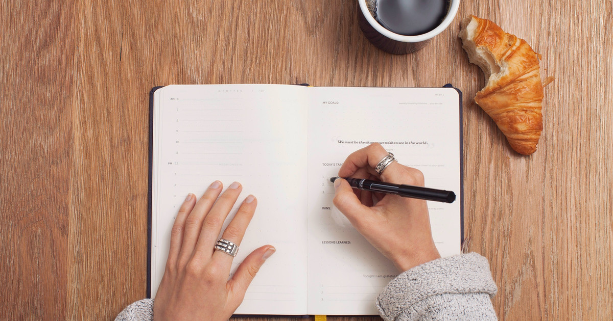 A person sitting at a table writing goals in a journal while planning meaningful activities, relationships and future aspirations.