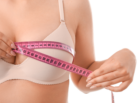 A woman measuring her breasts, representing the results of a breast reduction surgery.