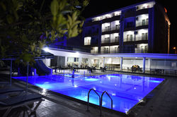 Demirci Otel’in gece aydınlatmalı bina ve yüzme havuzu görünümü