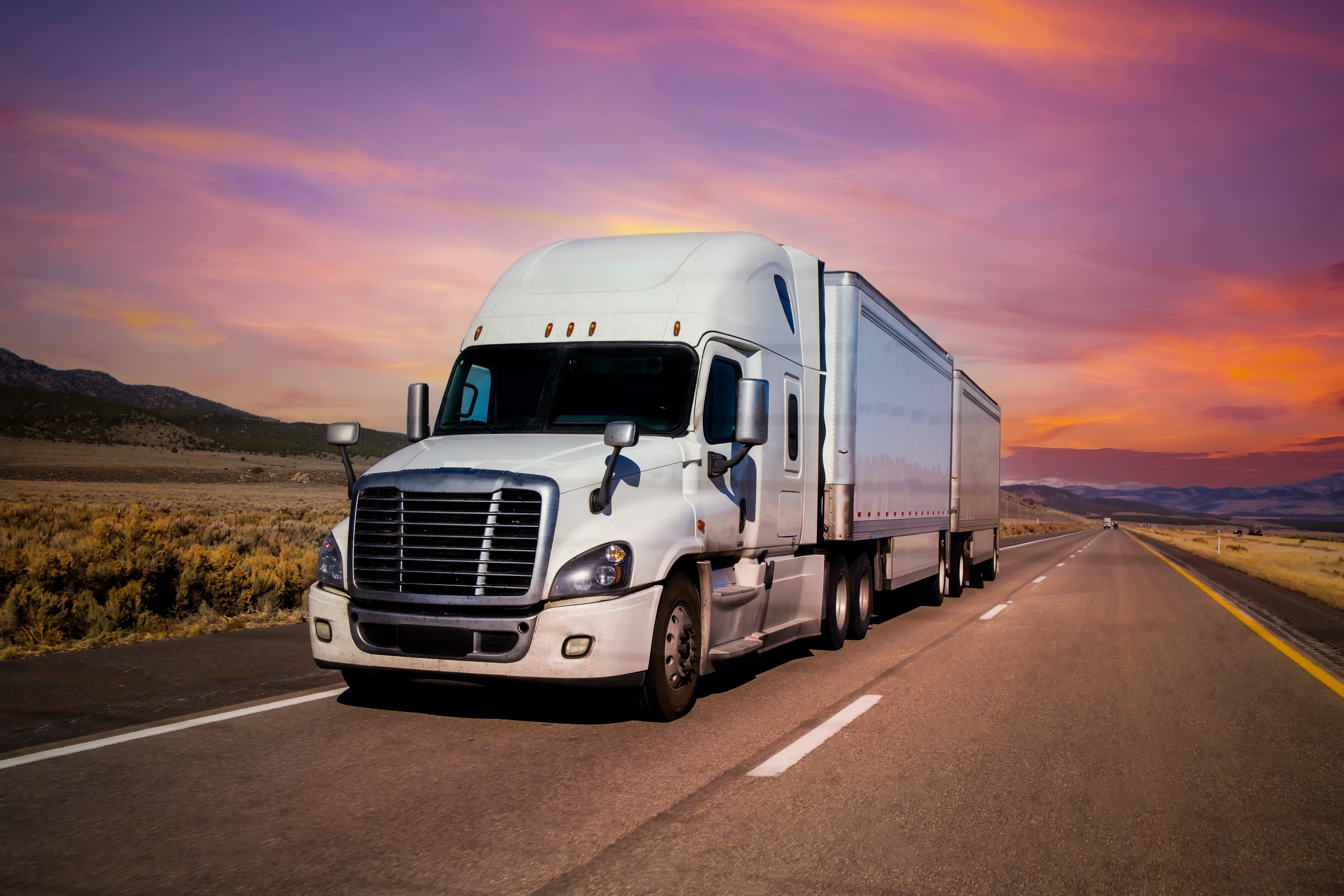 TCW tractor-trailer running an open desert highway at dusk