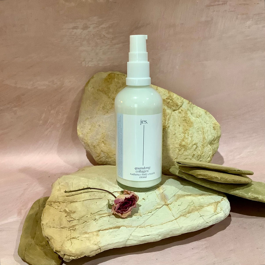Quandong Collagen Cream Bottle on Rocks with a rose