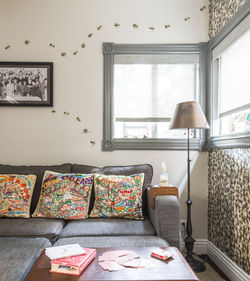 Modern living room with a gray sectional sofa, featuring vibrant pillows with detailed travel maps. 