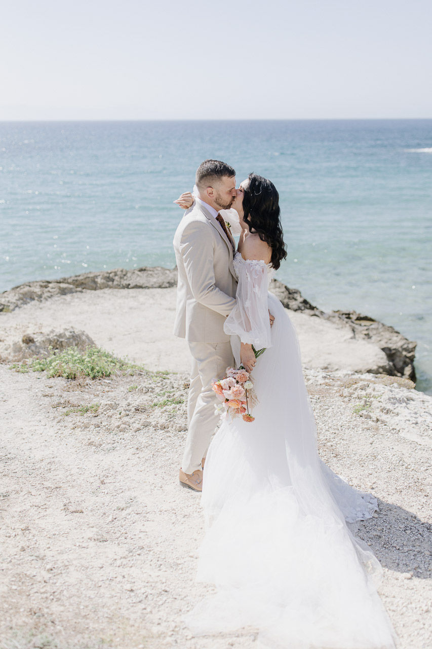 bride and groom kissing at the beach