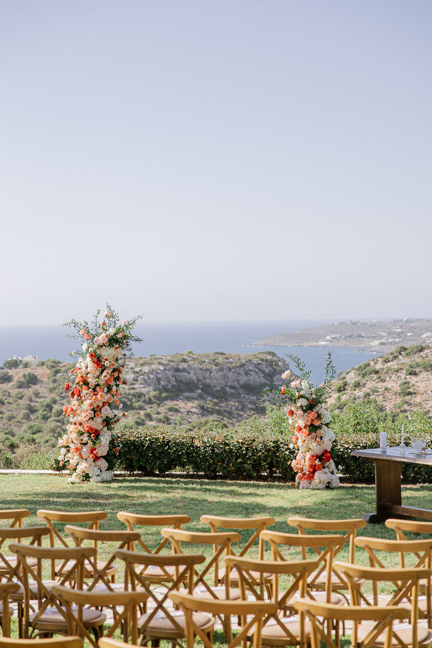 colourful flower arch, wooden chairs