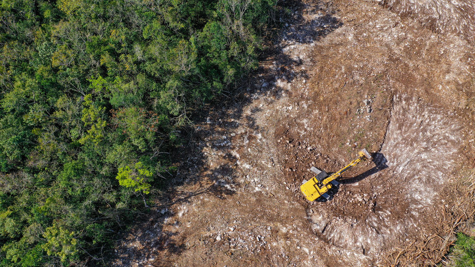 Aerial view of deforestation with excavator clearing land, illustrating unverified emissions in supply chains and the need for accurate deforestation data to achieve net zero targets. - Koltiva.com