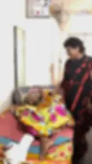 Neelam Mam talking compassionately with a bed-ridden elderly person at old age home
