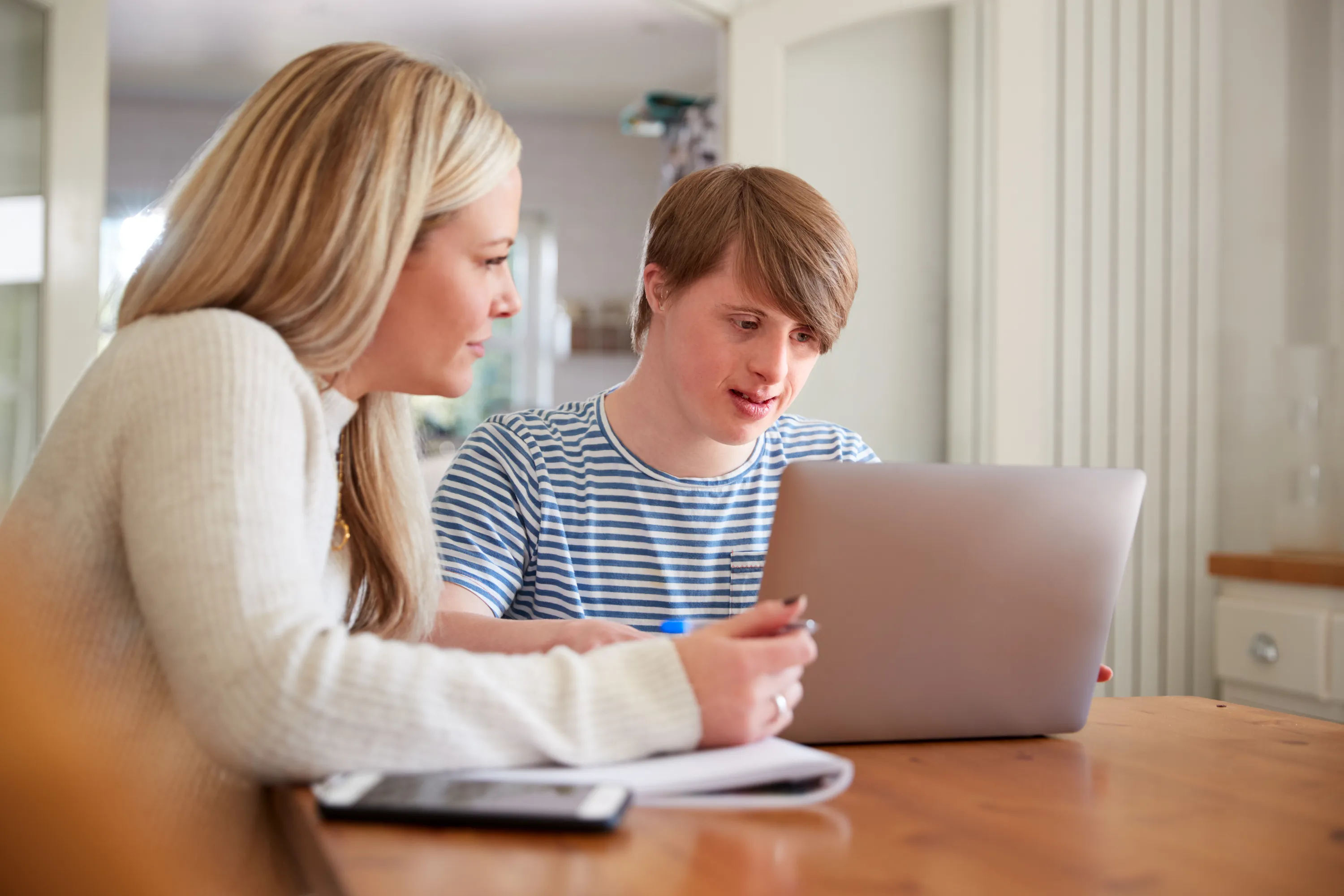 Two people talking together at a kitchen table indoors