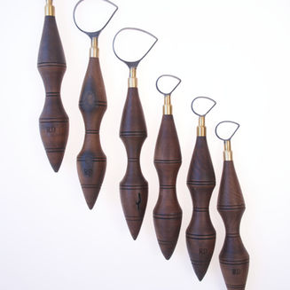 Créer une photographie éditoriale haut de gamme pour RD Tools & Pottery, une marque spécialisée dans les outils de tournassage en carbure de tungstène. Présenter trois formes distinctes de lames d’outils de tournassage : forme 7, forme D et forme poire, disposées clairement côte à côte. Ajouter des manches en bois élégants dans des tons de noyer, d’olivier et d’érable. Fond beige neutre, éclairage studio doux et directionnel, ombres subtiles, esthétique luxueuse, sobre et raffinée. Proportions réalistes des outils, lames métalliques bien définies, matériaux photoréalistes et composition épurée. Aucun texte, aucun logo, aucun objet supplémentaire. Format horizontal large 16:9, adapté à l’image principale d’un article de blog consacré au choix des formes de lames des outils de tournassage.