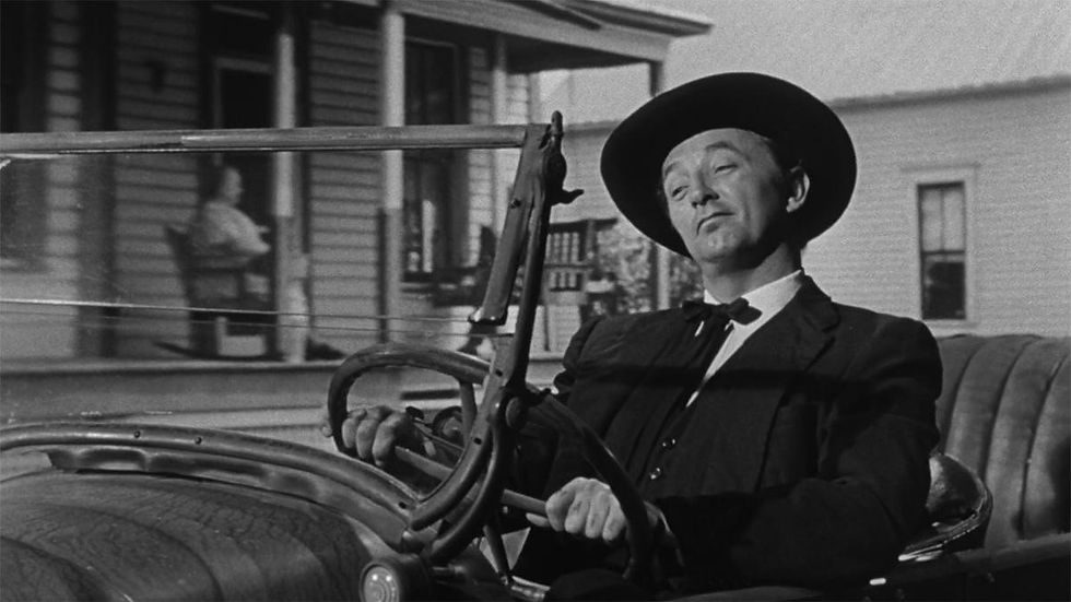Harry Powell (Robert Mitchum) drives through the countryside while addressing God as though divine approval were already assured. His private conversations expose the disturbing ease with which he transforms criminal intention into supposed religious duty.