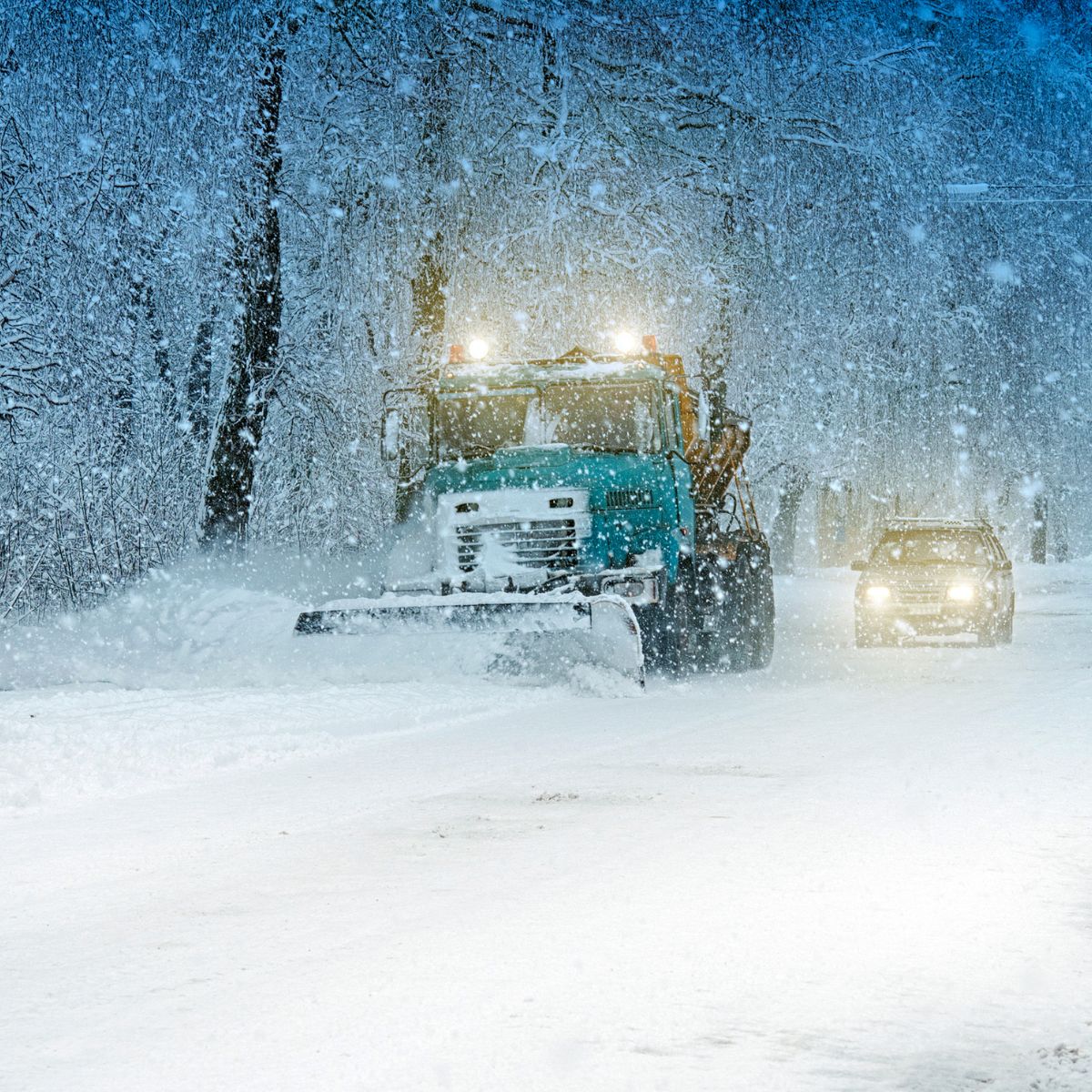 Snowplough truck working on a snow-covered road.