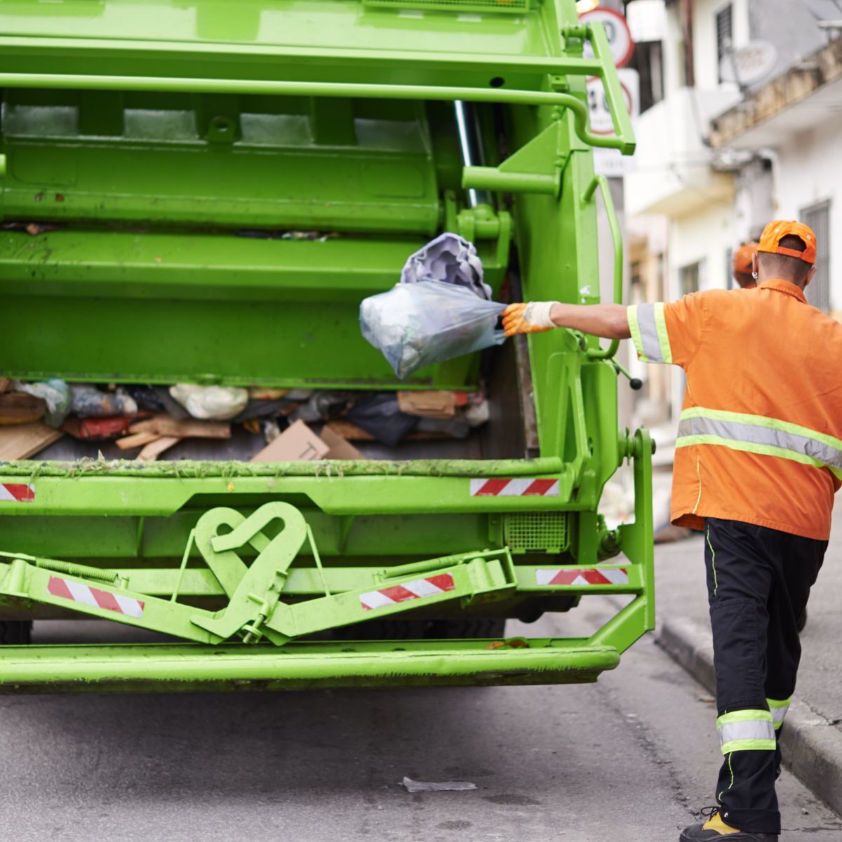 Worker at the rear of a waste collection truck.
