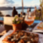 Prato de pizza especial, com cerveja artesanal e ao fundo a orla de Garopaba.