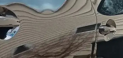 “Close-up of a car door with mirror-like reflection on the polished black paint.”