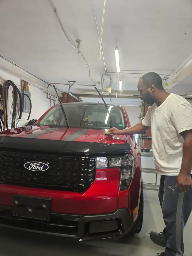 Technician at Mack2Steam applying a ceramic coating to a red Ford Maverick during the paint protection process in Holmen, Wisconsin.
