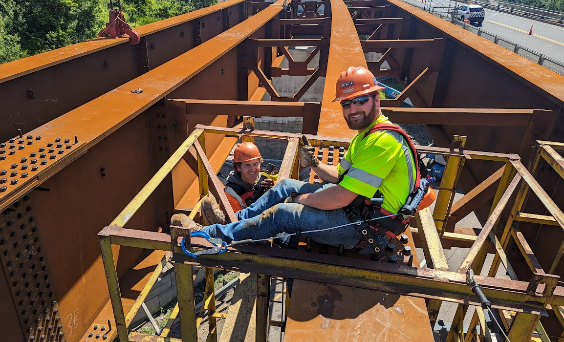 Employees in a man basket working on structural steel