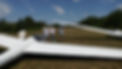 Instructor and students discuss cloud formations while standing near their gliders. 