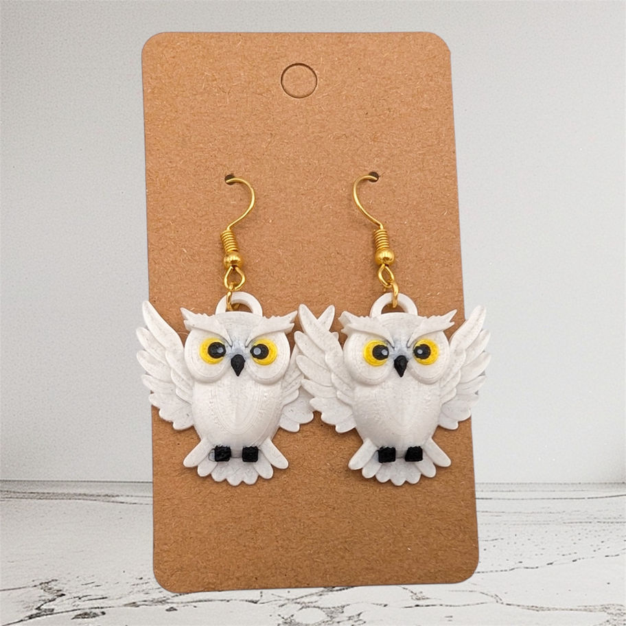 White owl earrings with gold hooks on a brown store display WBK.