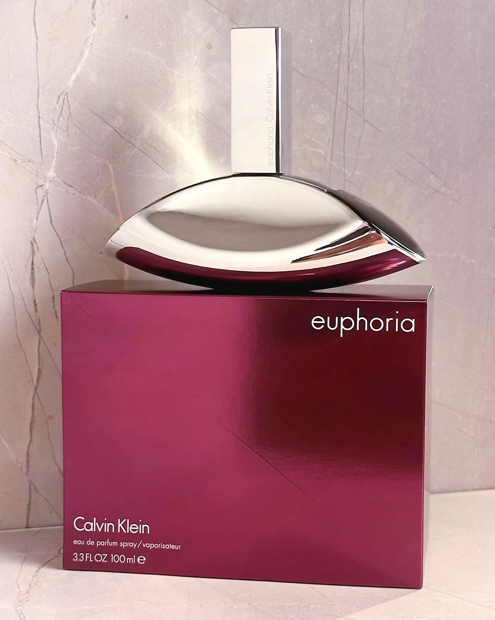 Vista frontal frasco perfume Euphoria Calvin Klein de 100ml sobre su caja en fondo marmol