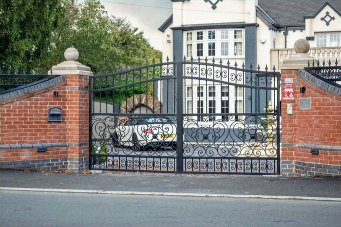 Double driveway gate with wrought iron design, finished in a matte black powder coat