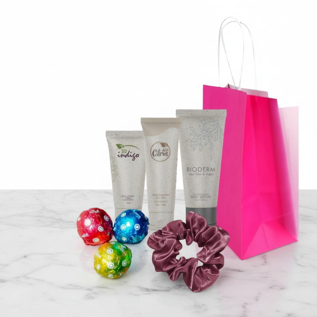 Set de autocuidado femenino con cremas, scrunchie y chocolates en bolsa de papel rosado – Amenidades BL