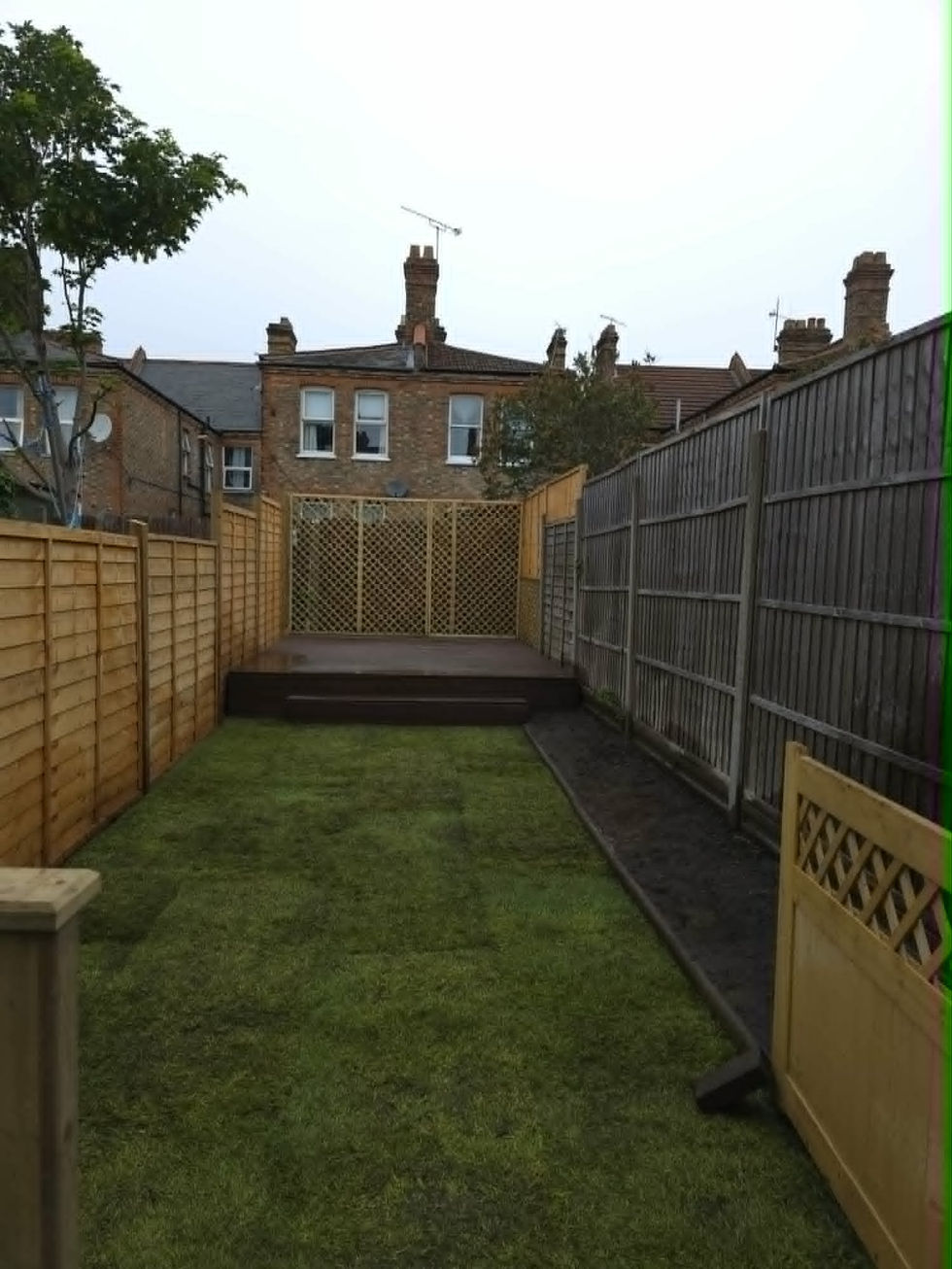 Completed garden renovation in Walthamstow, E17 - newly laid turf lawn, timber decking with trellis privacy screen, new fence panels and flower beds.
