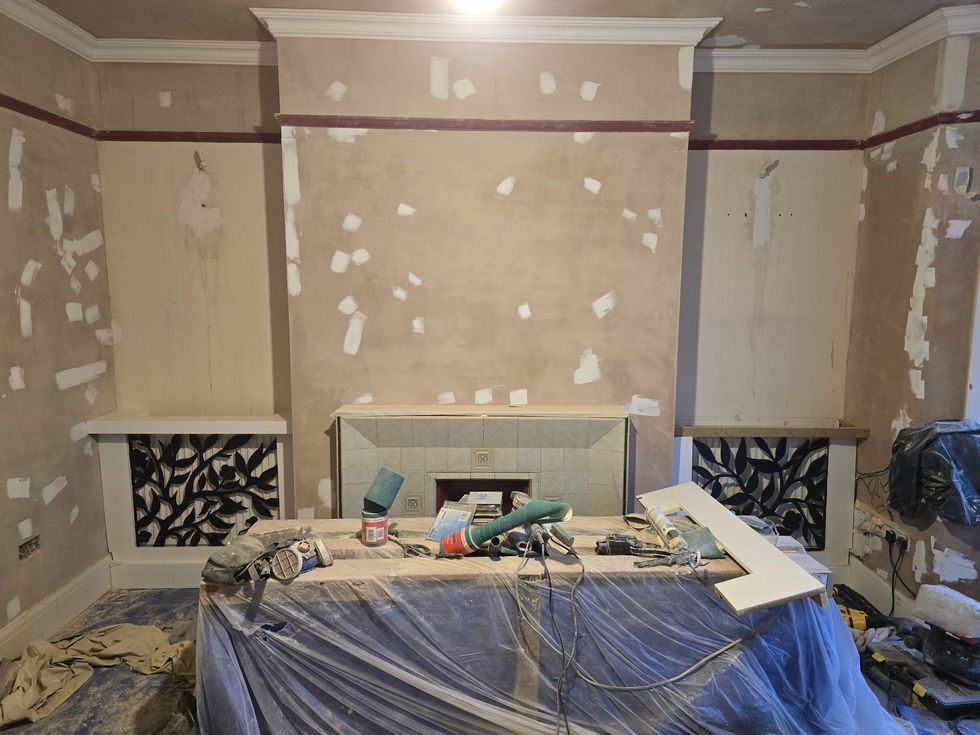 Wall preparation stage with exposed wiring channels, electrical back boxes, and construction materials on the floor before plastering.
