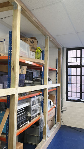 Bespoke designed and built commercial storage shelving with metal racking and timber supports, holding organised boxes and equipment.