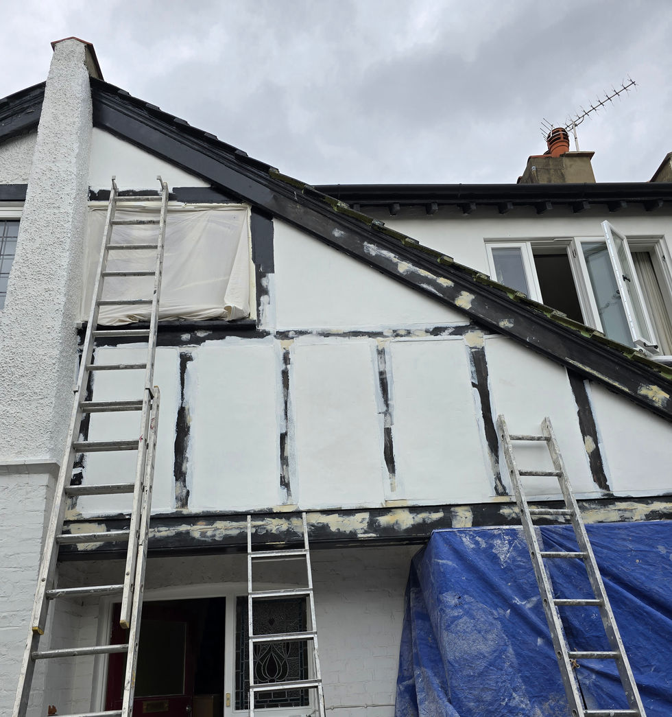 Exterior of a house in Ealing with ladders and protective sheeting in place during preparation for maintenance and repainting. 