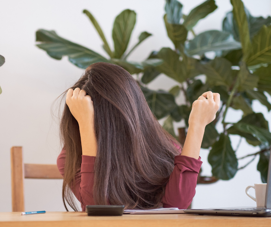 Stressed and anxious woman in the office in desperation sitting at her desk