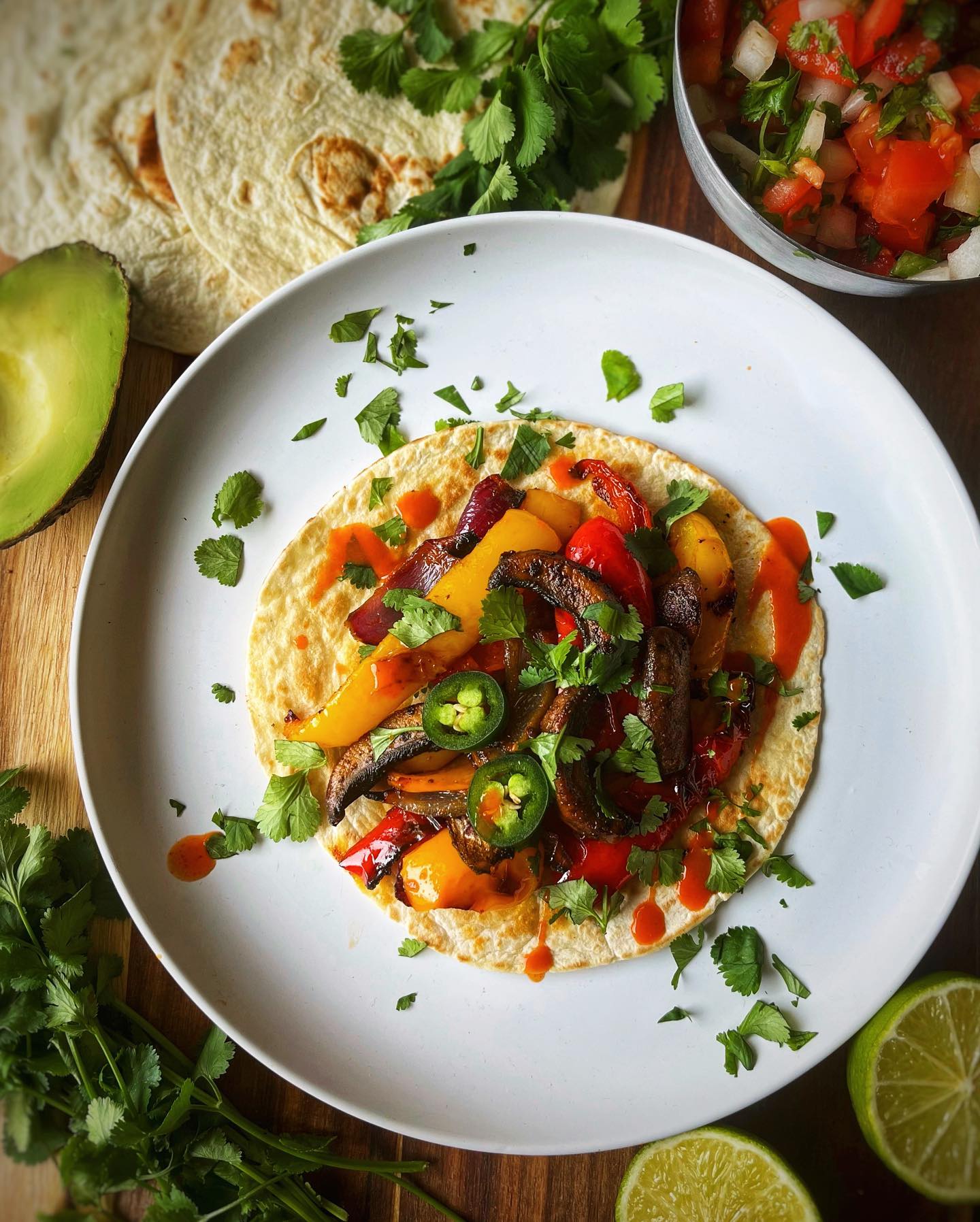 Smoky vegan veggie fajitas with peppers, mushrooms, red onion, avocado, and lime