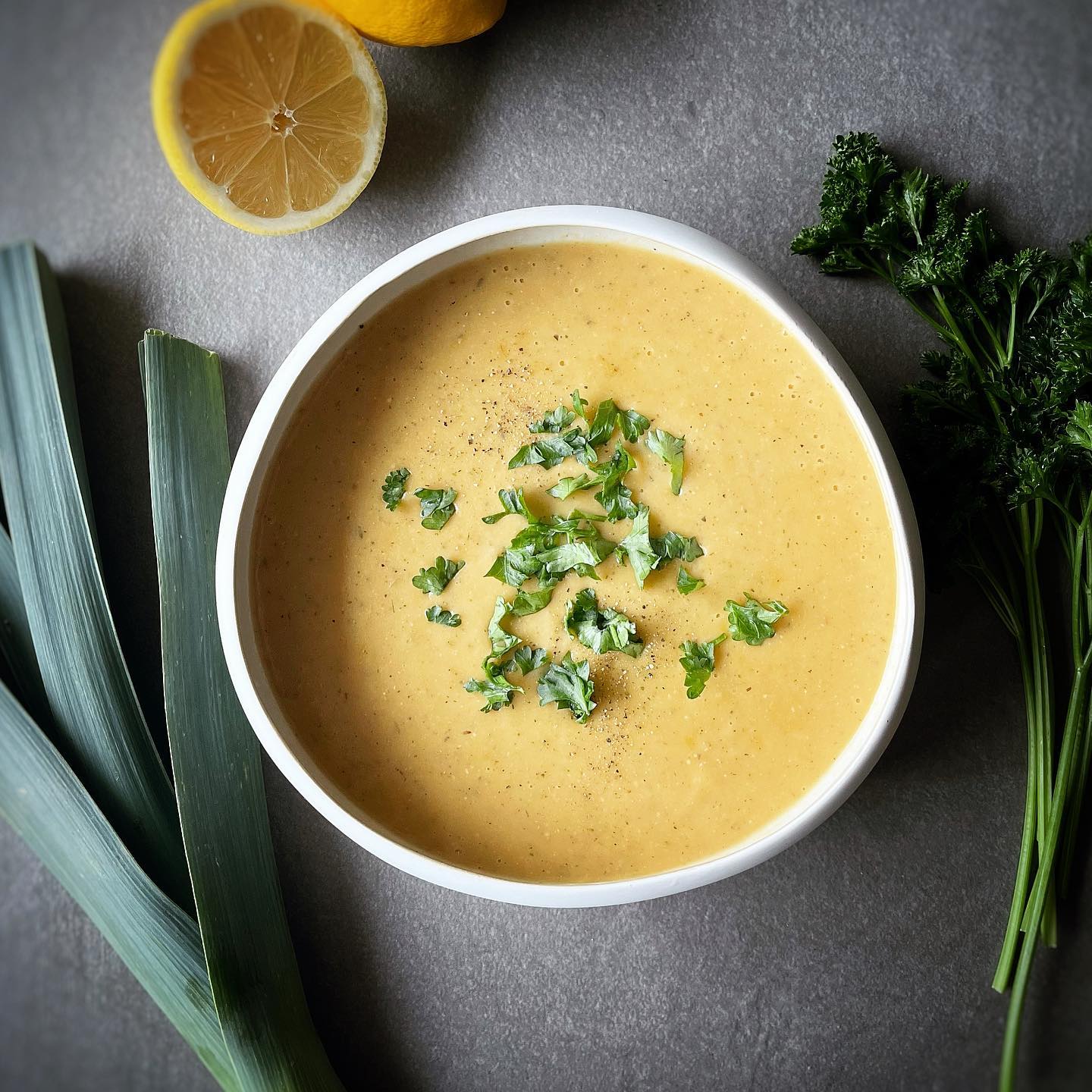 Creamy vegan potato leek soup garnished with parsley and black pepper