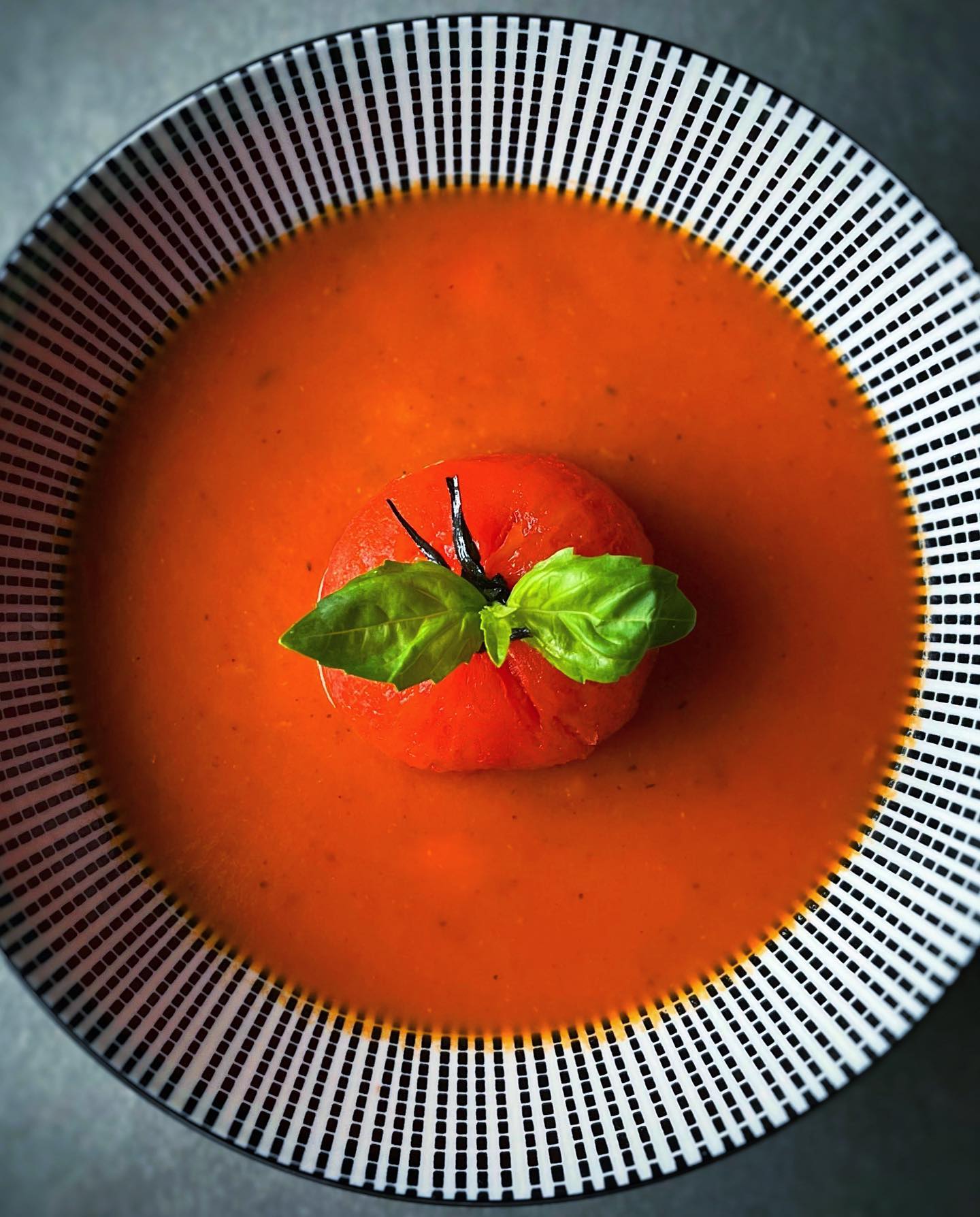 Smooth vegan tomato basil soup topped with roasted tomatoes and fresh basil