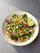 ensalada de maíz mexicana con hojas verdes variadas, aguacate, jalapeño, cilantro y feta vegano